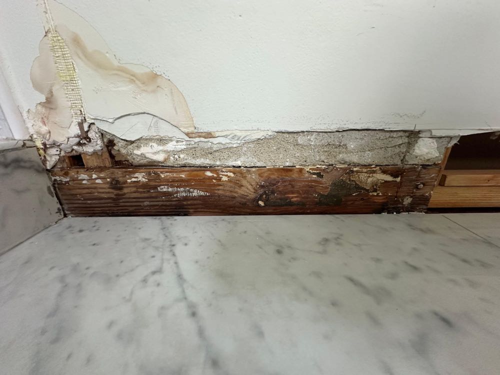 Hidden water damage and rot found behind a baseboard